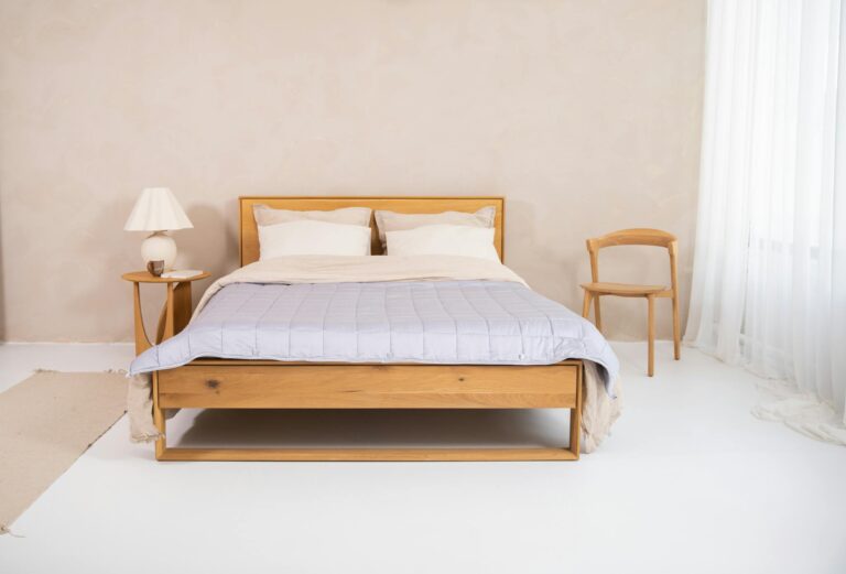 A serene minimalist bedroom with wooden bed frame, cotton bedding, and cozy decor.