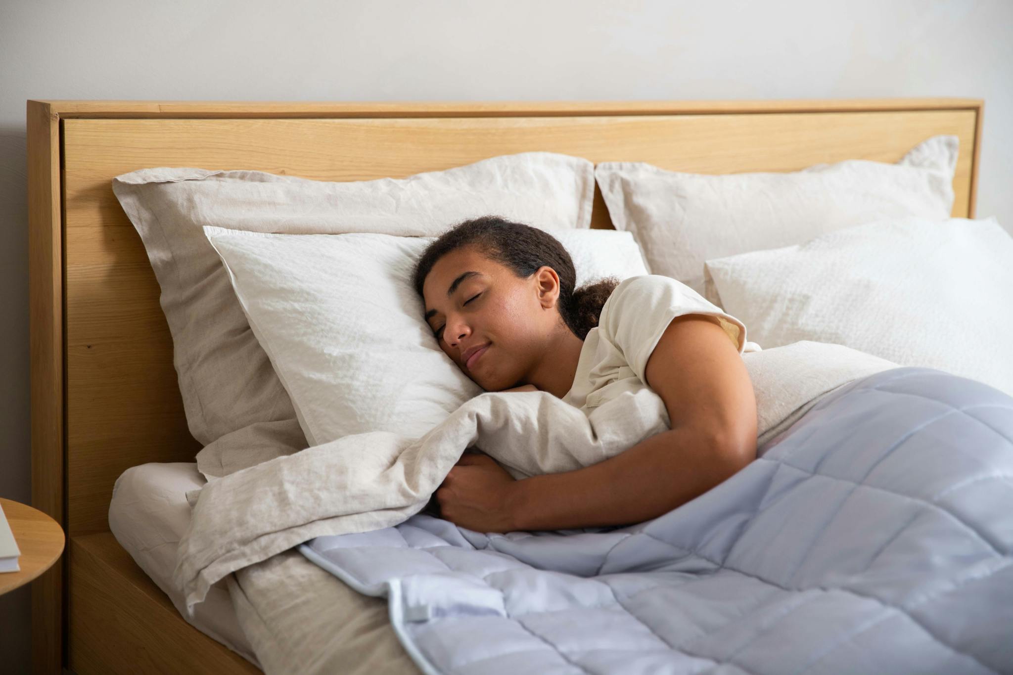 Adult resting under a cozy duvet in a serene bedroom setting promoting relaxation and wellness.